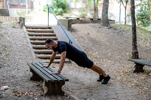 This young man is committed to his fitness goals, incorporating exercises on a park bench into his outdoor workout routine