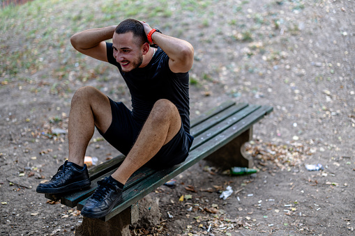 Maintaining strength and vitality, this young man engages in a rigorous workout, making use of a park bench as part of his outdoor fitness regimen