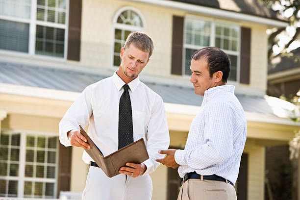 Real estate agent showing brochure in front of house