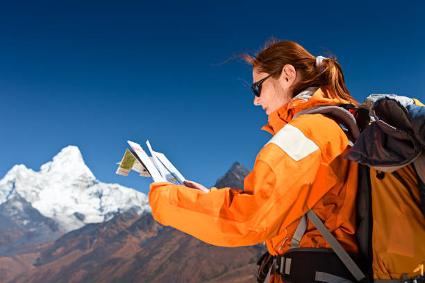 Female trekker studying a map, mount Ama Dablam on background