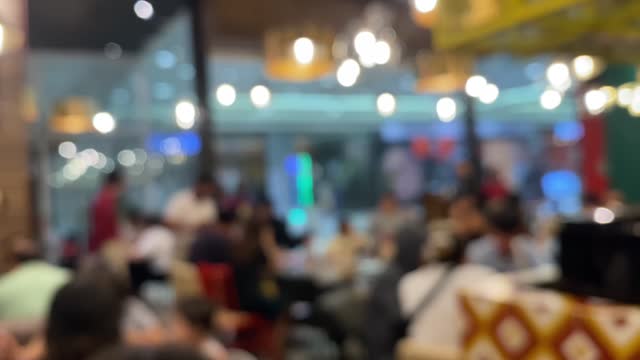 Blurred image inside a cafe, waiters serving visitors. Out of focus.