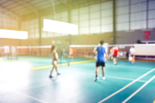 Blurred image of badminton playing in indoor badminton court, concept for badminton sport playing after work or in daily life every where.