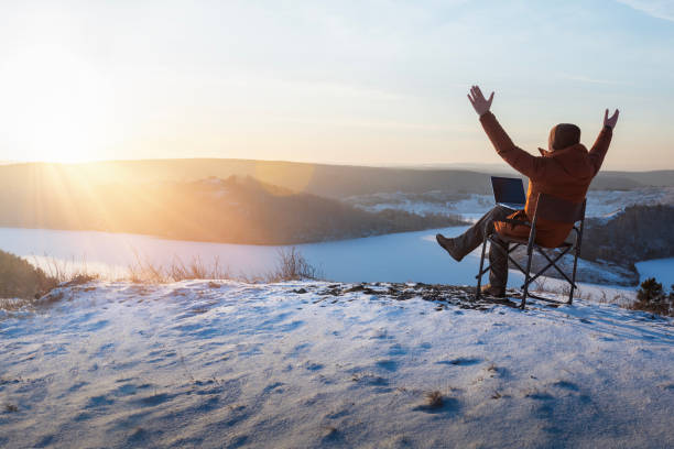 istock happy man with laptop working outdoor in winter. businessman sitting using computer and  enjoying winter. freedom, remote work concept. 1831462254