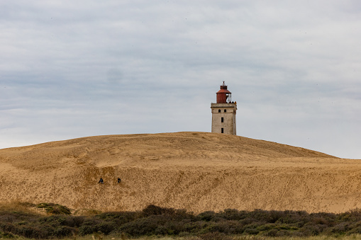 Rubjerg Knude Lighthouse, Denmark Nov 1, 2023 A view of the famous Rubjerg Knude lighthouse that was moved due to dune and water erosion in 2018, and people walking.