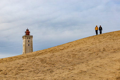 Rubjerg Knude Lighthouse, Denmark Nov 1, 2023 A view of the famous Rubjerg Knude lighthouse that was moved due to dune and water erosion in 2018, and people walking.