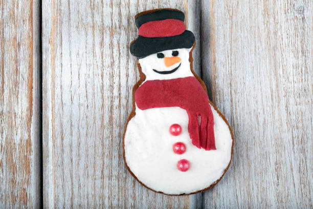 istock Festive Christmas Gingerbread Cookie Snowman on white rustic wooden table 1831521435