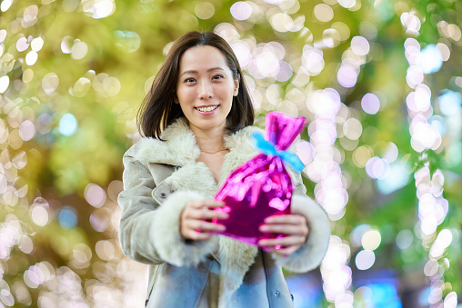 A woman holding a colorfully wrapped present outdoors at night
