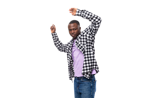 positive young american man in casual shirt dancing on white background with copy space.