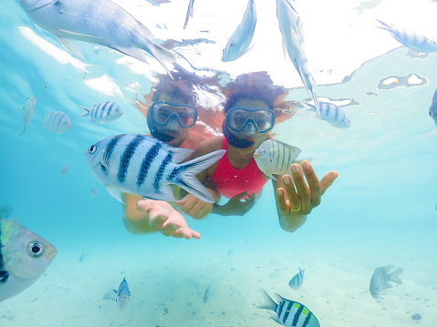 A couple of men and a woman on a snorkeling trip at Samaesan Thailand. dive underwater with Nemo fishes in the coral reef sea pool. couple swim activity on a summer beach holiday