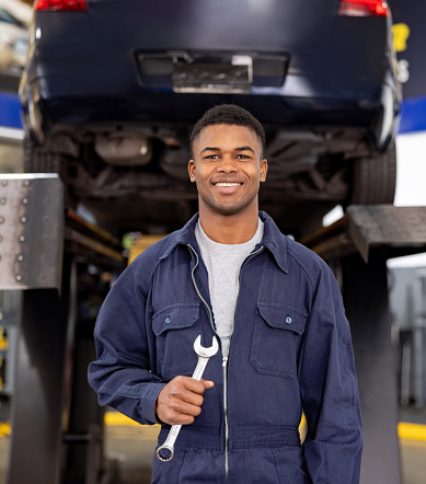 Portrait of a happy African American mechanic working at an auto repair shop and looking at the camera smiling