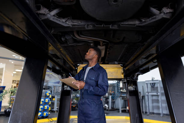 istock Mechanic fixing a car at a garage and taking notes on a clipboard 1831594605