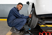 Happy mechanic changing a flat tire at an auto repair shop
