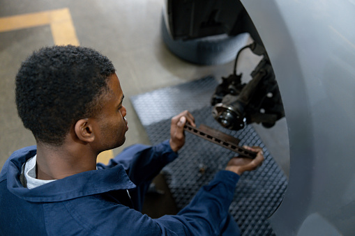African American mechanic fixing a flat tire on a car at an Auto Repair Shop