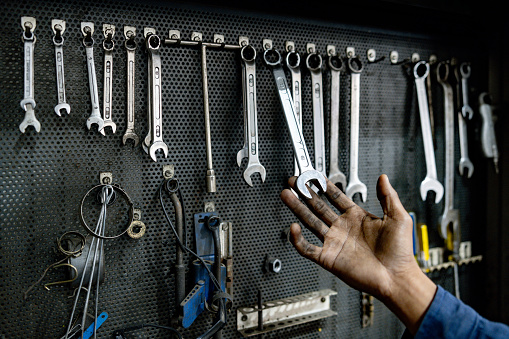 Close-up on a mechanic grabbing a wrench from a tool kit at an auto repair shop
