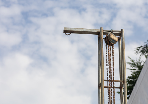 Jacked chain hoist mounted on a steel pole on a blue sky background.