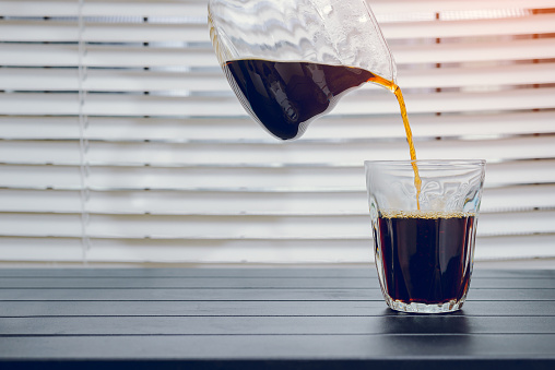 Pouring coffee into a glass on the table