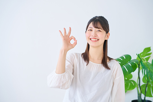 Young woman giving an OK hand sign indoors