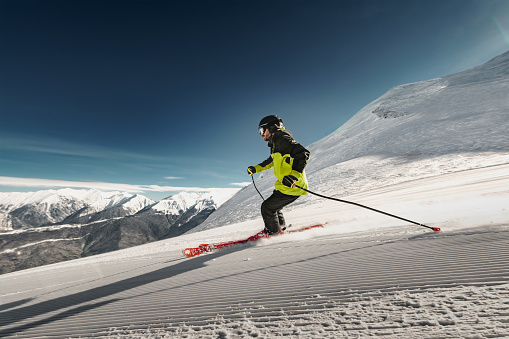 Fast professional skier is riding on ski slope at clear day. Ski resort concept