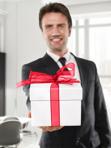 Businessman smiling and holding a gift box in an office