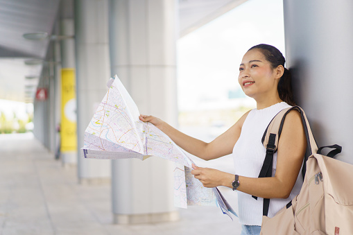 Happy beautiful Asian female backpack traveler explore the city and landmark on a map, woman backpacker tourist looking - exploring the city street on a map.