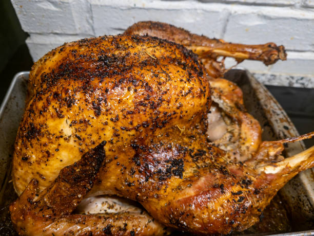 A cooked whole roast turkey with seasonings in a deep pan for thanksgiving dinner