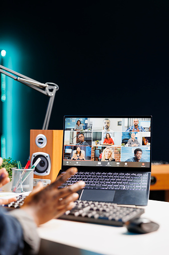 Detailed view of laptop screen displaying group of people on a video conference call. African American person working at home, having virtual communication with coworkers on wireless computer.