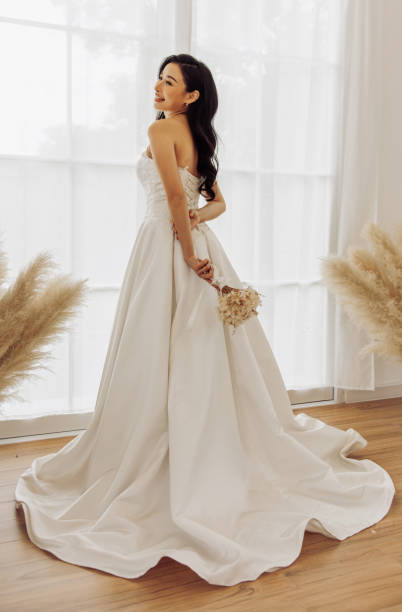 mariée rayonnante dans une robe élégante près de la fenêtre avec un rétro-éclairage doux - wedding dress wedding domestic room bride photos et images de collection