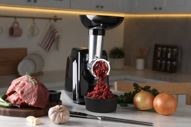 istock Electric meat grinder with beef mince and products on white marble table in kitchen 1831757379