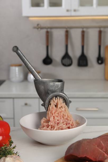 istock Metal meat grinder with chicken mince and products on white table in kitchen 1831759191