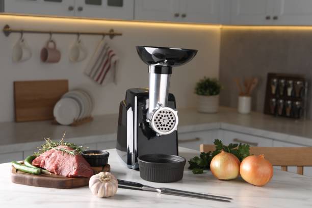 istock Electric meat grinder with beef mince and products on white marble table in kitchen 1831760766
