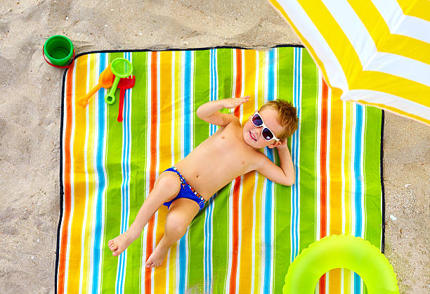istock happy kid sunbathing on colorful beach 183176722