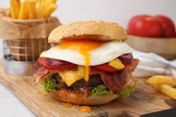 istock Delicious burger with fried egg on white wooden table, closeup 1831794037
