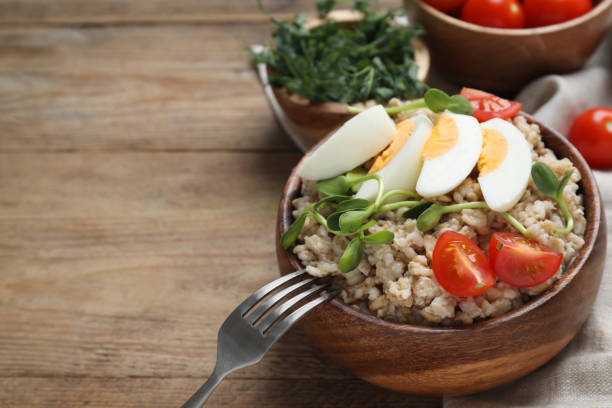istock Tasty boiled oatmeal with egg, tomatoes and microgreens served on wooden table, space for text 1831796431