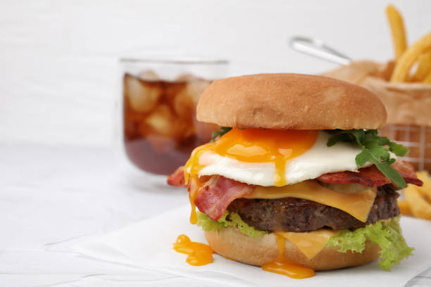 istock Delicious burger with fried egg on white table, closeup. Space for text 1831797179