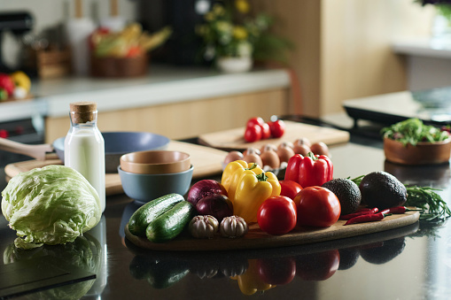 Closeup of set of food on kitchen table, focus on vegetables and bottle of milk