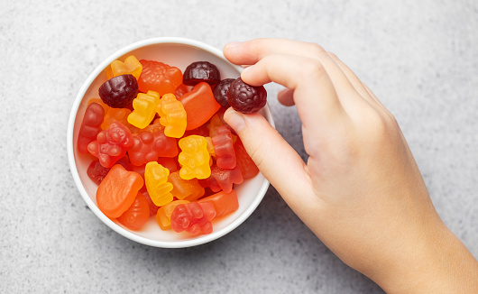 Chewable gummy bears vitamins and supplements.  A girl holds a gummy bear vitamines in her hands.