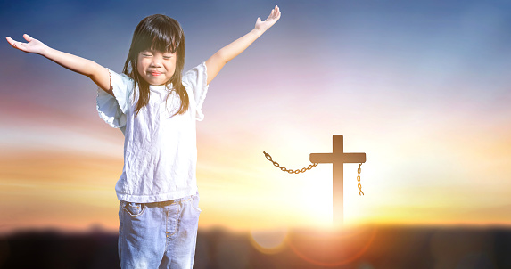 little child girl praying and worship on cross background
