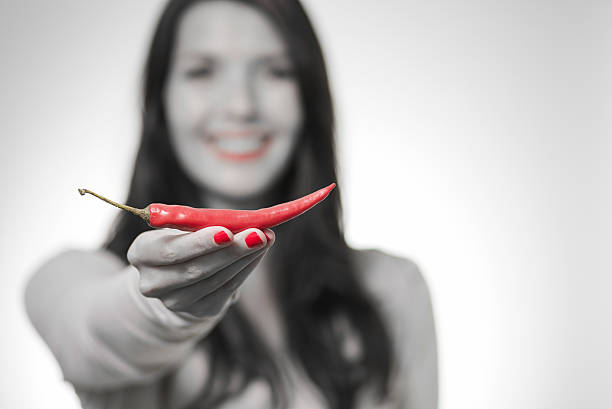 Red juicy hot pepper in a woman's hand. On a light green background.