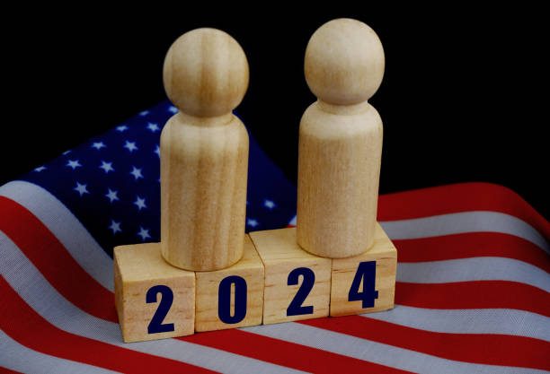 istock Two people figures on cubes with numbers 2024 on wavy US national flag. 1831867048