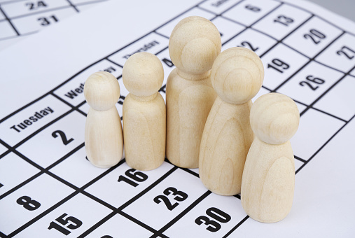 Wooden family people figures on calendar background. Family events concept.