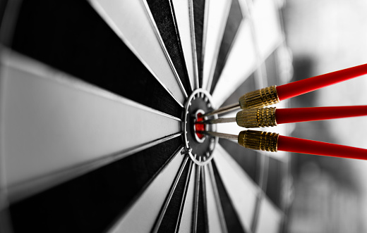 Dart board with three darts in the red bull's-eye