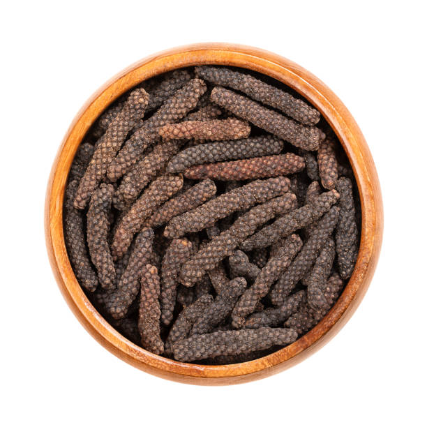 Dried long pepper catkins, fruits of Piper longum, in a wooden bowl Dried long pepper catkins, in a wooden bowl. Fruits of Piper longum, sometimes called Indian long pepper or pippali. Used as spice and seasoning, with a similar taste than its relative black pepper. capsicum annuum longum stock pictures, royalty-free photos & images