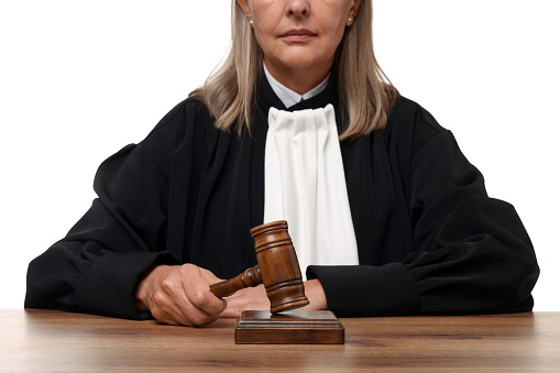 Judge with gavel at wooden table on white background, closeup