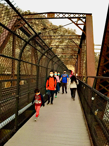 Harpers Ferry, West Virginia, USA - December 12, 2020: A family walks along the Goodloe E. Byron Memorial Pedestrian Walkway, a part of the Appalachian Trail, on a railroad bridge crossing the Potomac River.