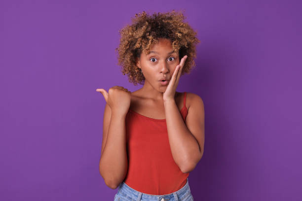istock Young surprised attractive African American woman points finger stands in studio 1831976121