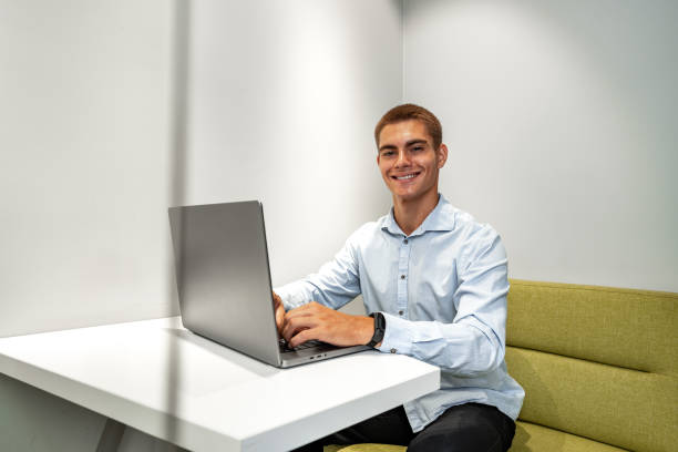 istock Handsome young businessman sitting in office lobby with a laptop 1831984993