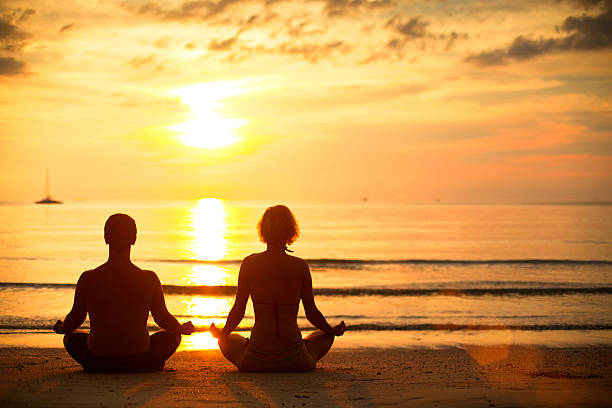 istock Young couple practicing yoga on the beach at sunset. 183200486