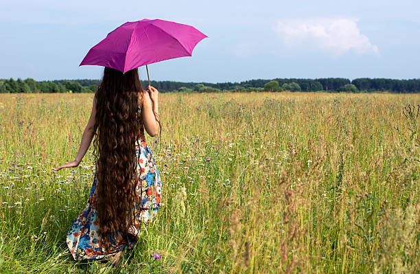 Young beautiful woman with color umbrella in field