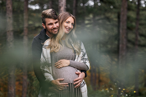 Happy couple enjoying nature. Woman is pregnant, babies coming soon.