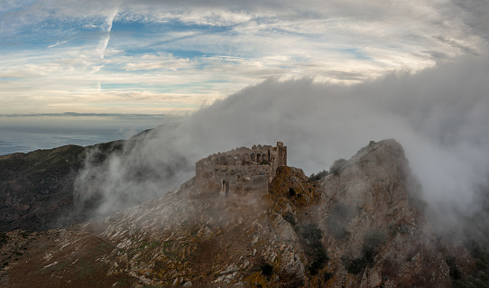 Magazzini, Italy - 14 November, 2023: drone view of the Castello del Volterraio shrouded in morning fog and cloud